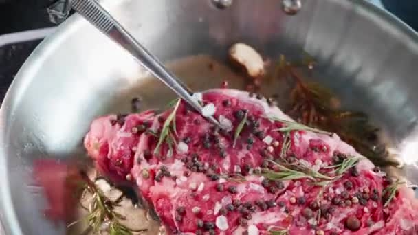 Lo chef usa le pinze per trasformare la bistecca di carne succosa fritta in una padella, primo piano . — Video Stock