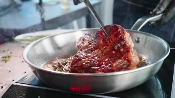 Chef usa pinças para transformar o bife de carne suculento frito em uma frigideira, close-up . — Vídeo de Stock