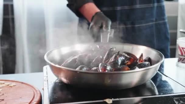 Silbando mejillones en la sartén. Chef que mezcla mariscos con aceite y condimentos — Vídeo de stock