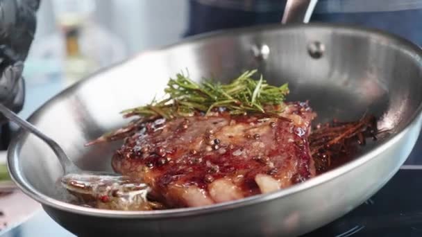 Meat steak is fried in oil and grease on frying pan, close-up in slow motion. — Stock Video