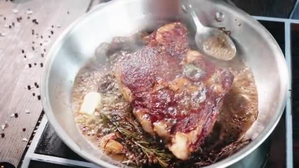 Bife de carne é frito em óleo e graxa na frigideira, close-up em câmera lenta . — Vídeo de Stock