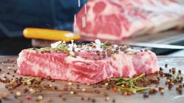 Espolvorea una gran sal blanca sobre la carne cruda, de cerca en cámara lenta . — Vídeos de Stock