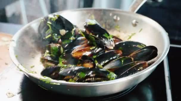 Шипение мидий на сковородке. Шеф-повар смешивает морепродукты с маслом и приправами — стоковое видео