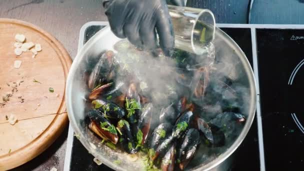 Le chef verse du vin dans une poêle à frire avec des moules sifflantes et met le feu par un brûleur à gaz — Video