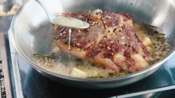 Мясо стейк жареный в масле и жир на сковороде, крупным планом в замедленной съемке . — стоковое видео
