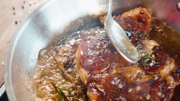 La bistecca di carne è fritta in burro e grasso su padella per friggere, primo piano in movimento lento . — Video Stock