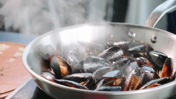 Kocken saltning musslor på väsande stekpanna. — Stockvideo