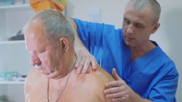 Sjukgymnasten utför behandlingar med en äldre patient — Stockvideo