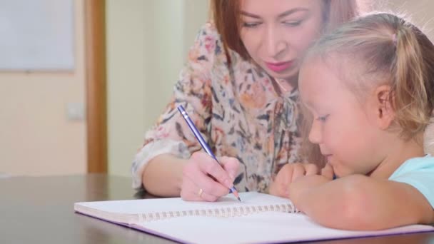 Malá roztomilá holka sedí v učebně a studií s učitelem v knize cvičení — Stock video