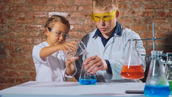 Mężczyzna naukowiec z niewiele uczennica prowadzi eksperyment chemiczny razem — Zdjęcie stockowe