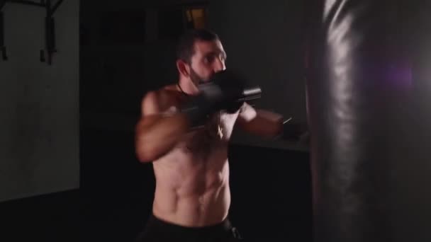 Man boxer att göra slår på en boxning väska. Fighter träning inomhus — Stockvideo