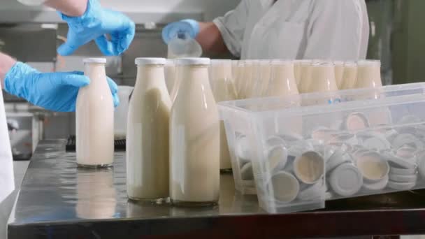 Werknemers een melk in flessen vullen door handen in melk fabriek — Stockvideo