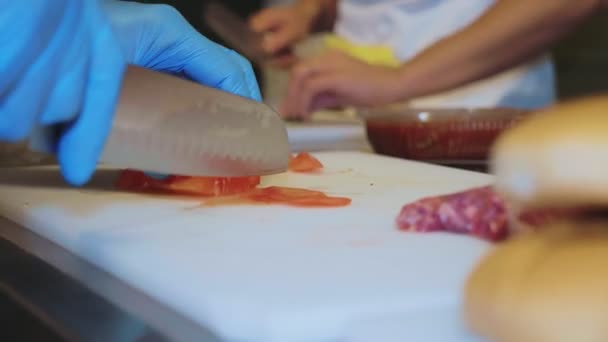 Häuptlinge Hände in Handschuhen schneidet Tomate, Nahaufnahme — Stockvideo