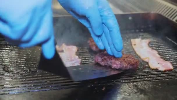 Close-up asar hamburguesas chuleta en la superficie de freír mientras jefe pone un jamón cerca — Vídeo de stock