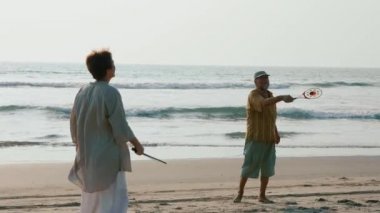 Ağır çekimde plajda Tai chi ballon top oynarken üst düzey çift.