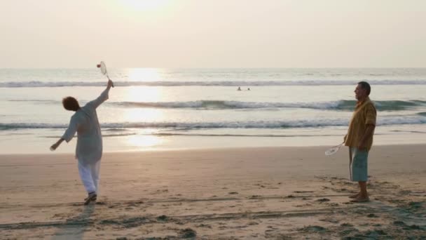 Actieve senior paar tai chi ballon bal spelen op het strand in slow motion. — Stockvideo
