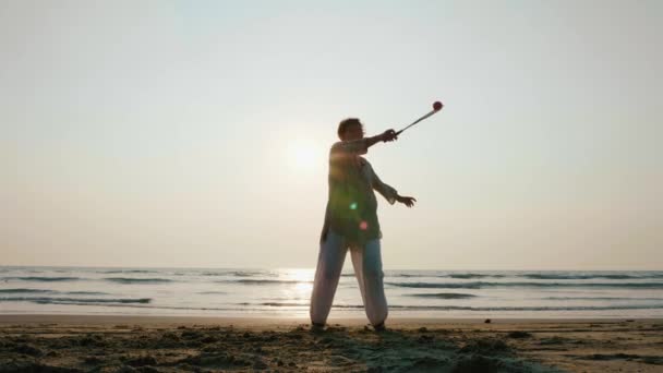 Starší žena cvičí tai chi míč balon na pláži při západu slunce — Stock video