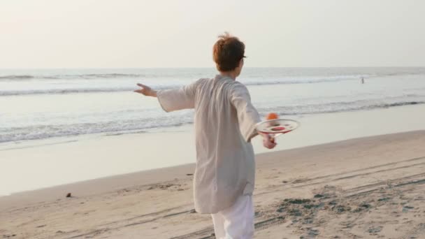 Senior woman practicing tai chi balloon ball on the beach at sunset — Stock Video