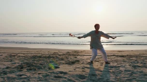 Senior Kvinna tränar tai chi ballong boll på stranden vid solnedgången — Stockvideo