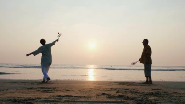 Aktives Seniorenpaar spielt Tai Chi Ballon Ball am Strand in Zeitlupe. — Stockvideo