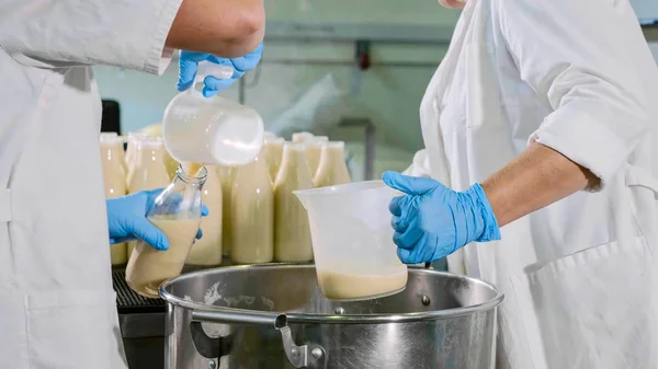 Trabajadores llenando una leche en botellas con las manos en la fábrica de leche —  Fotos de Stock