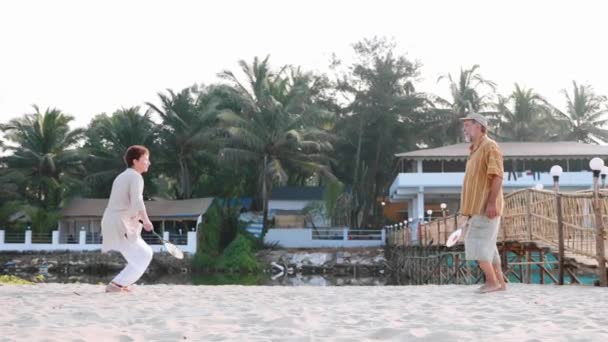 Pareja mayor activa jugando tai chi ballon ball en la playa en cámara lenta . — Vídeos de Stock