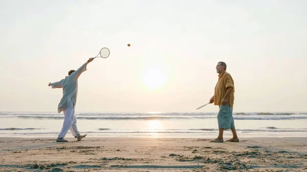 Ativo casal sênior jogando tai chi bola de balão na praia . — Fotografia de Stock