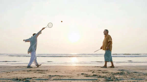 Pareja mayor activa jugando tai chi ballon ball en la playa . — Foto de Stock