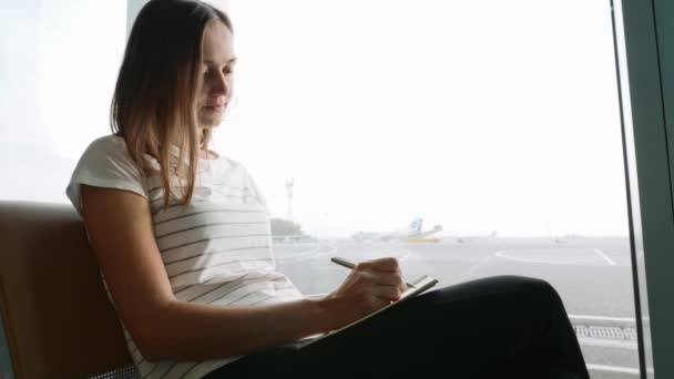 Mujer joven escribiendo en el diario en el aeropuerto — Vídeos de Stock