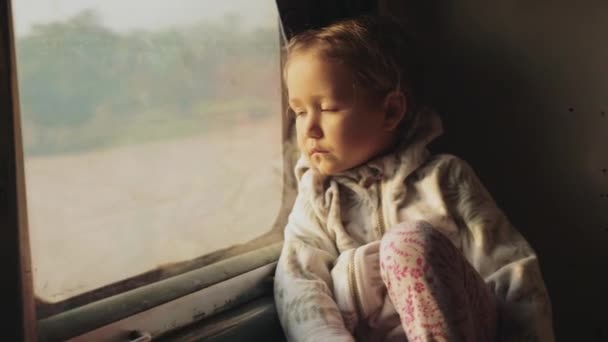 Lilla barn flicka tittar ur en asiatisk tågfönstret — Stockvideo