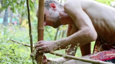 Bambu ahşap bahçe doğal çit oluşturmak için kullanan bir beyaz adam