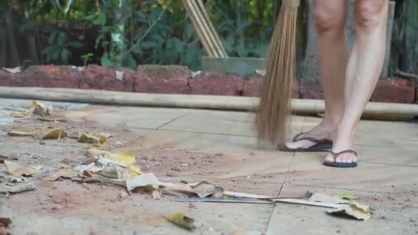 Närbild av en kvinna sveper en torra löv utomhus — Stockvideo