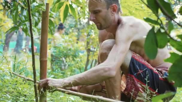 Un hombre caucásico usando madera de bambú para construir valla natural en el jardín — Vídeo de stock