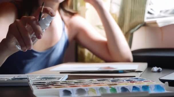 Een jonge vrouw hydrateert de verf voor het schilderen met aquarel, slow-motion — Stockvideo