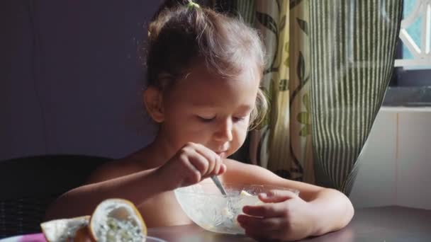 Barnet är att ha frukost. Porträtt av lilla söta tjejen äter gröt. — Stockvideo