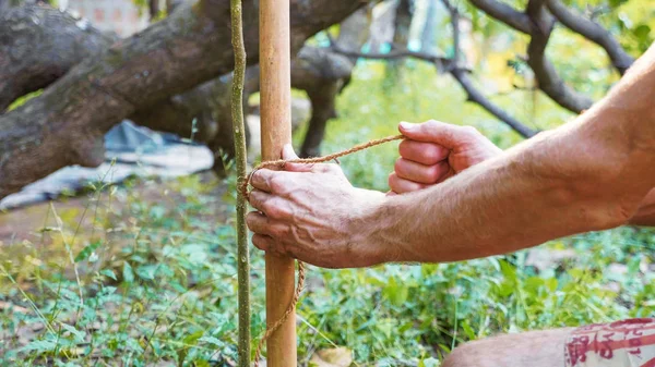 Kaukaski mężczyzna za pomocą bamboo drewna do budowy ogrodzenia naturalny w ogrodzie — Zdjęcie stockowe