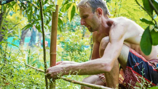 Kaukaski mężczyzna za pomocą bamboo drewna do budowy ogrodzenia naturalny w ogrodzie — Zdjęcie stockowe