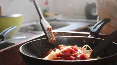 Pişirme ve kızartma tavada karıştırarak kırmızı domates soslu spagetti.