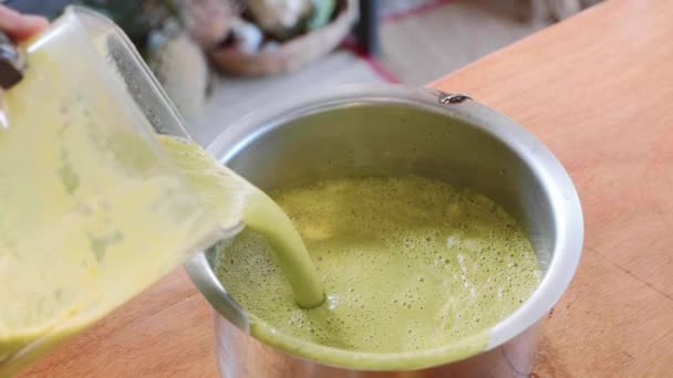 Cook χύνει μια κρεμώδη σούπα πράσινο σπανάκι στην κατσαρόλα από μπλέντερ — Αρχείο Βίντεο