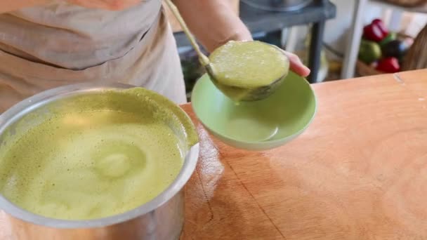 Повар наливает зеленый шпинат сливочный суп в миску из кастрюли — стоковое видео