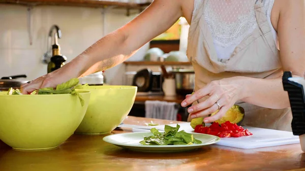 Mujer joven preparando una ensalada. Cocinar poner las hierbas en el plato para ensalada —  Fotos de Stock