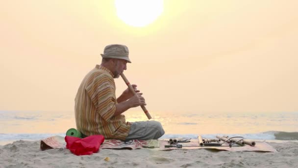 Senior mannen spelar bambu flöjt på stranden vid solnedgången — Stockvideo