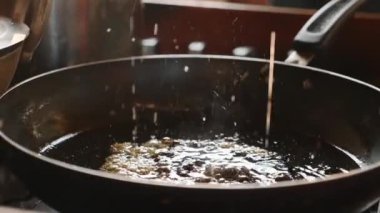 Kahverengi şeker tavada pişirme tatlı, ağır çekimde yakın çekim için bitkisel yağ içinde erime. Tatlılar yemek pişirmek için şeker şurubu yapma süreci.