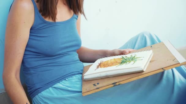 Jovem artista feminina pintando um abacaxi por aquarelas — Vídeo de Stock