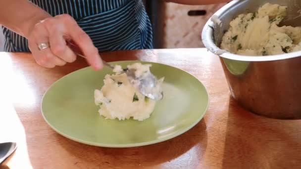 Close-up of cook serving mashed potatoes prepared with herbs in white plate. — Stock Video