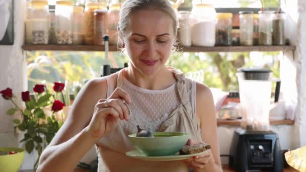 Young happy woman tasting just preparing food in the kitchen. — Stock Video