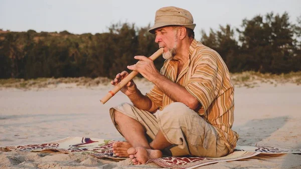 Homem sênior tocando flauta de bambu na praia — Fotografia de Stock