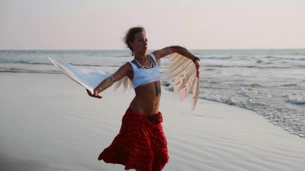 日没のダンスの天使の翼を持つ少女 スローモーションで砂浜で女性アーティストのダンス — ストック動画