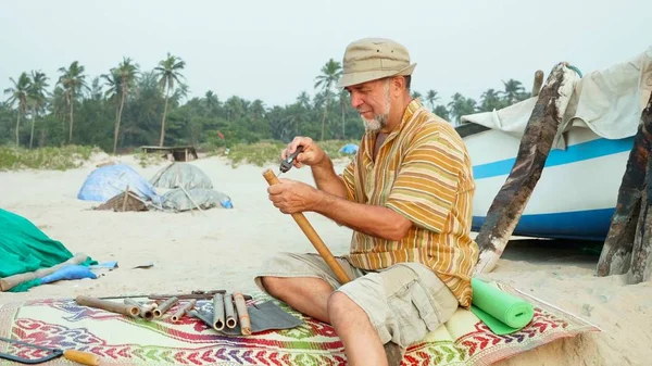 Homem Sênior Senta Praia Faz Flauta Pelas Mãos Buracos Perfuração — Fotografia de Stock