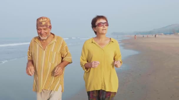 Couple senior actif courant sur la plage de sable au lever du soleil — Video